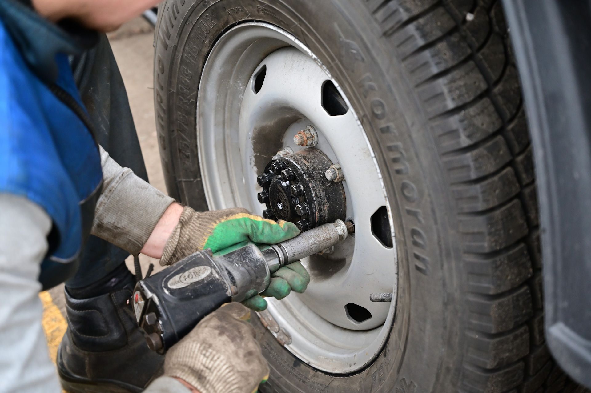 A person is working on a tire with an air wrench.