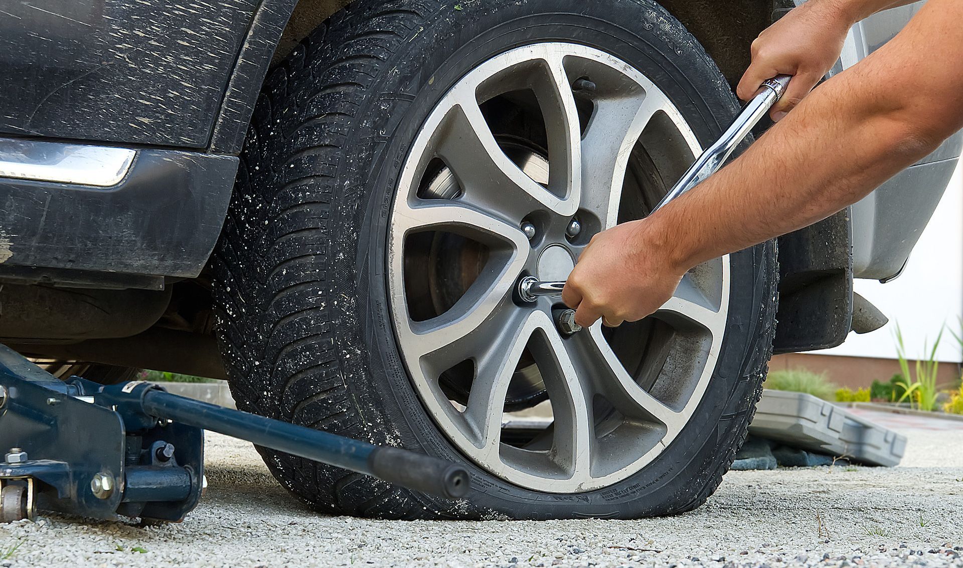 A man is changing a tire on a car with a wrench.