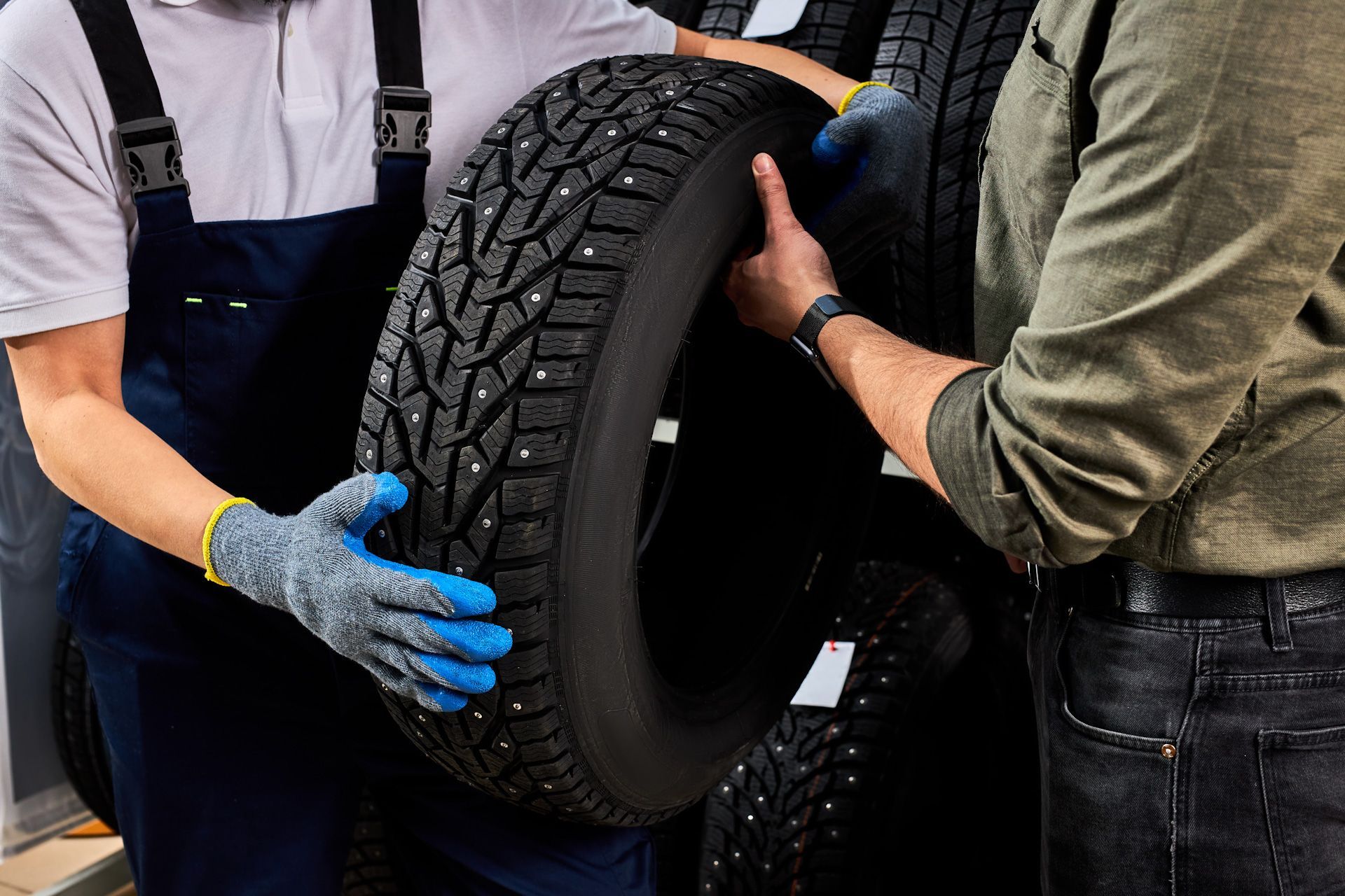 A man and a woman are holding a tire in a garage.