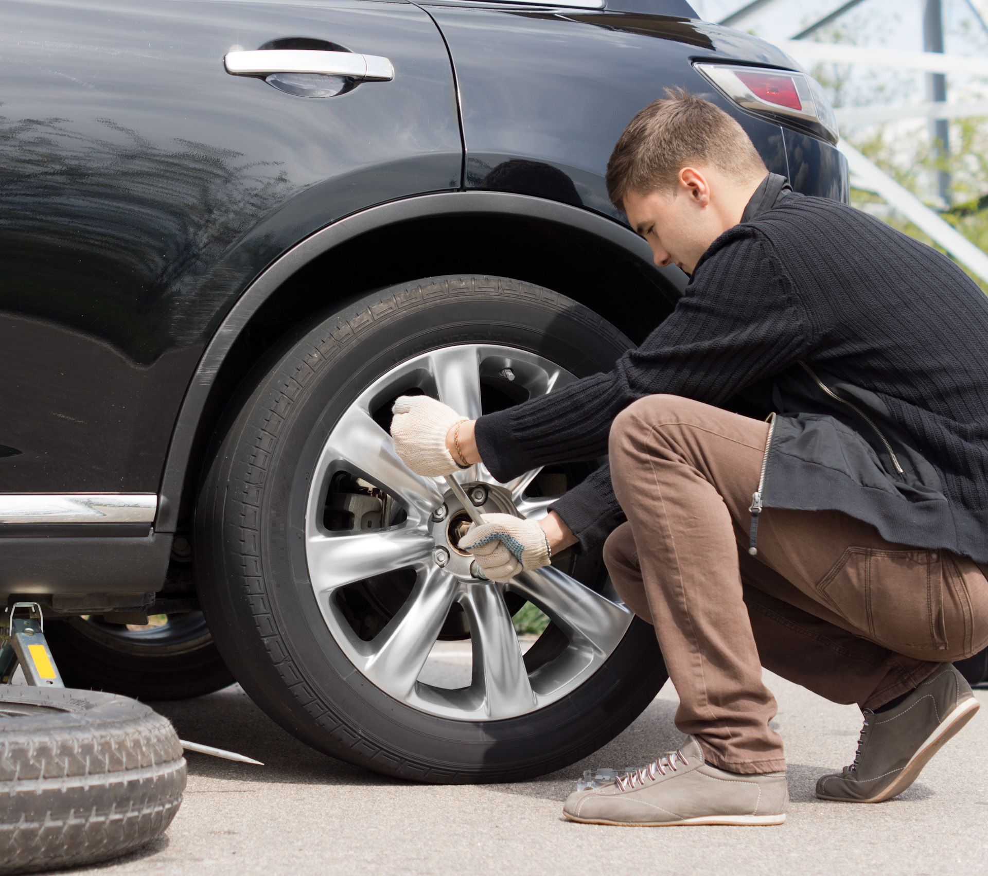 A man is changing a tire on a black car