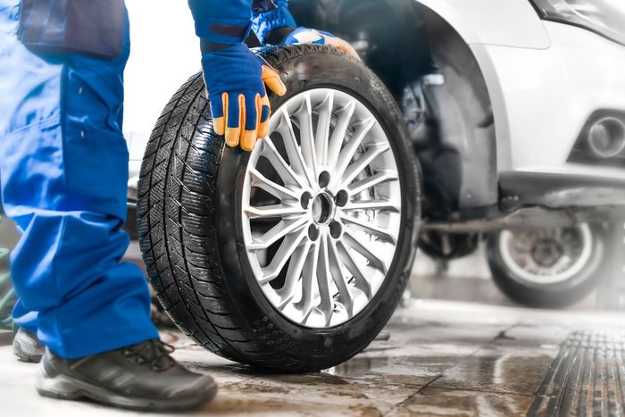 A man is putting a tire on a car wheel.
