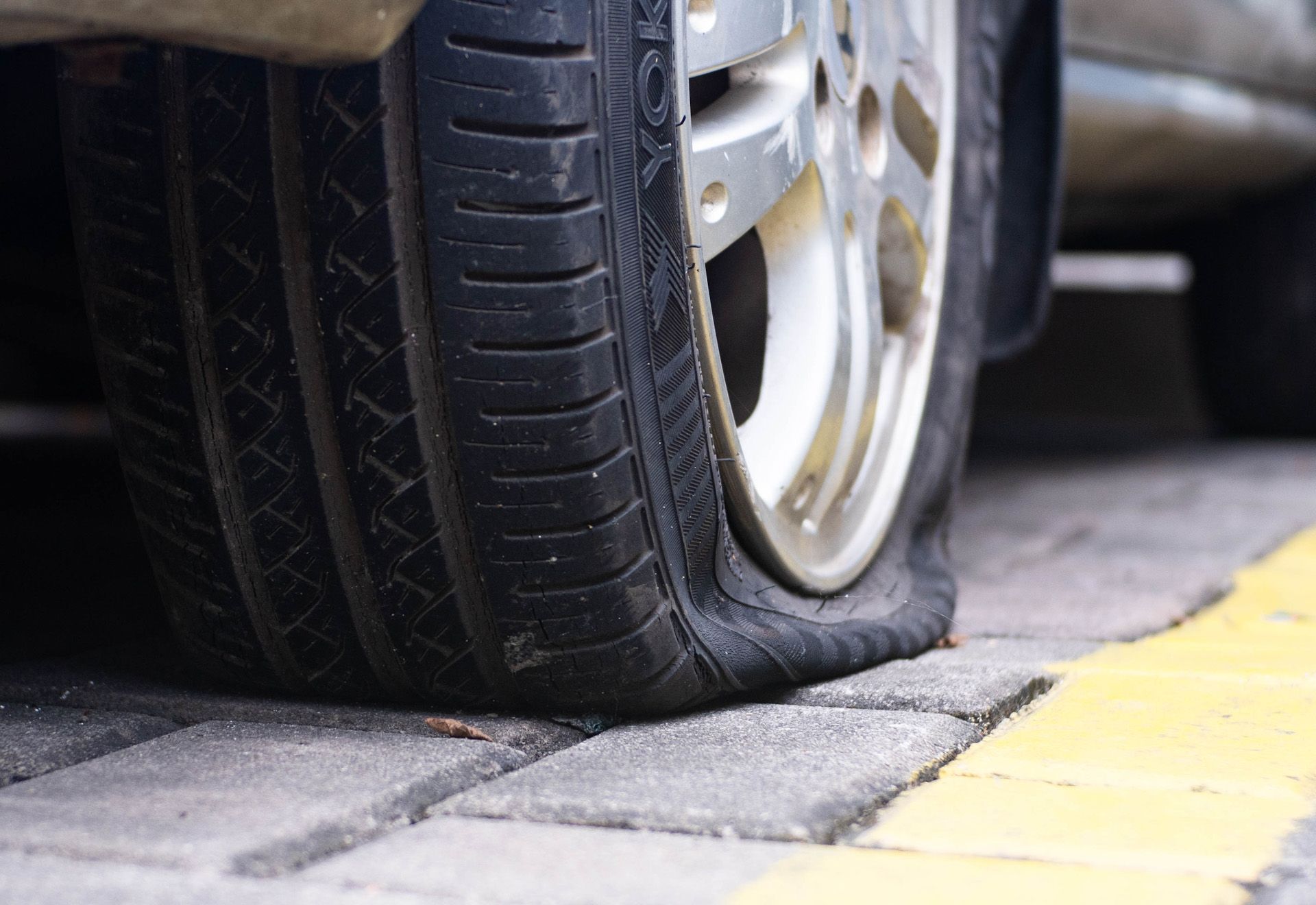 A car with a flat tire is parked on the side of the road.