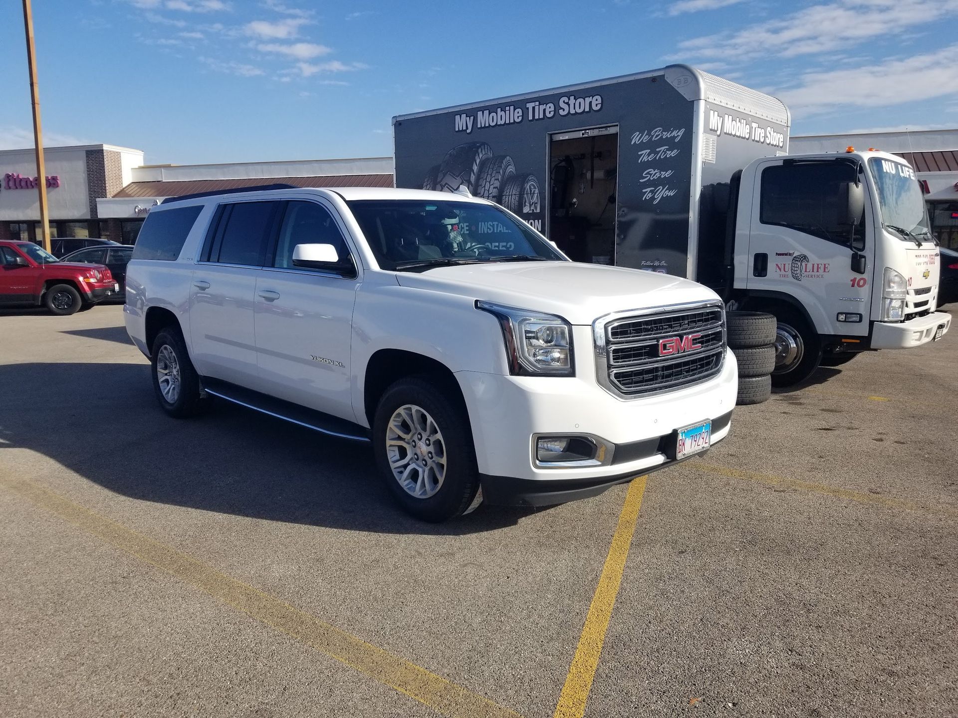 A person is holding a tire in front of a car.