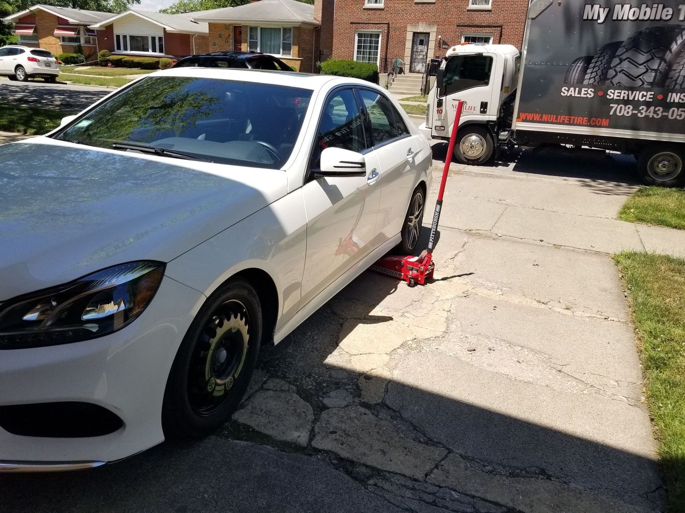 A man is changing a tire on a car in a garage.