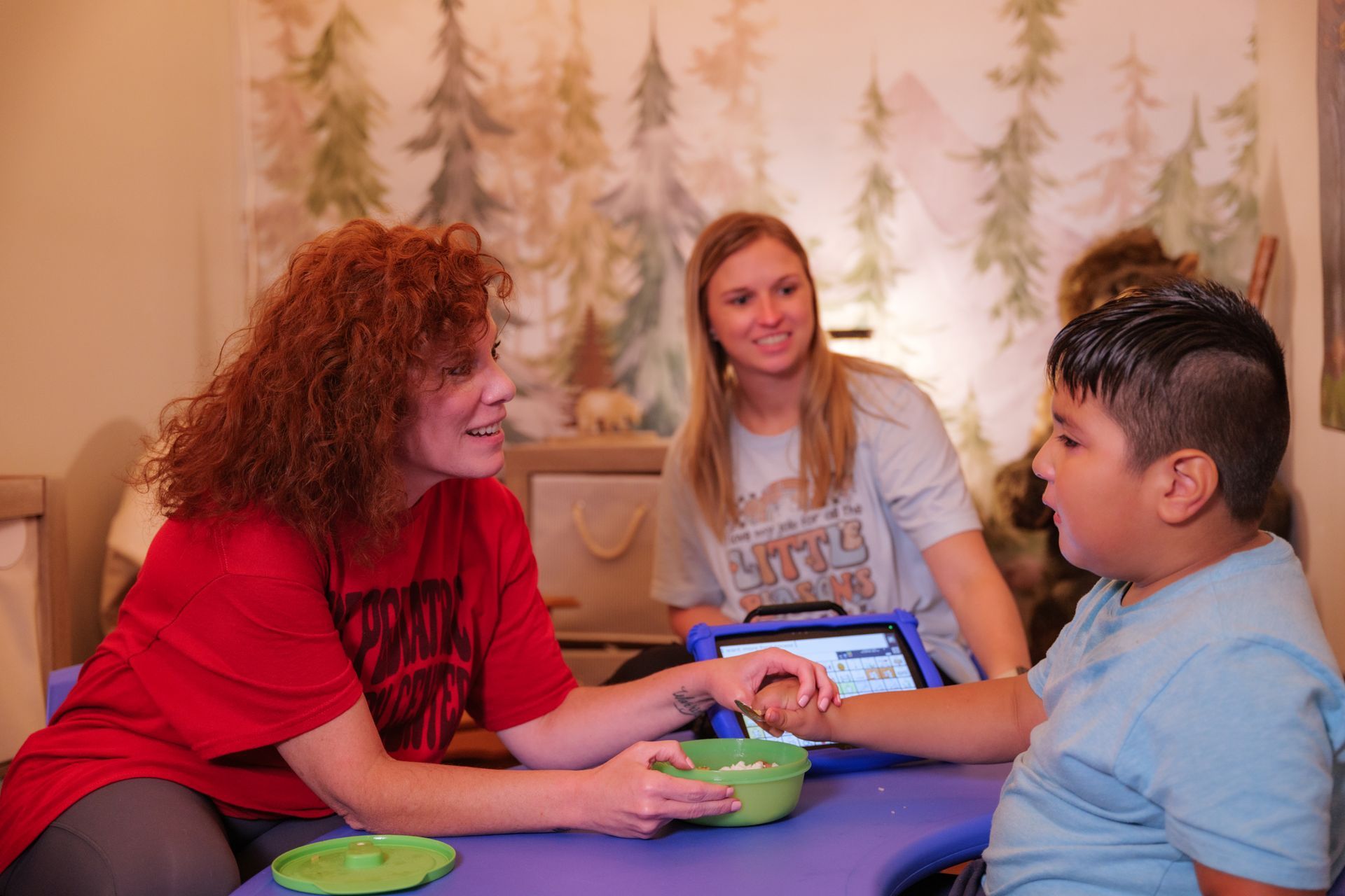 A woman and a boy are sitting at a table talking to each other.