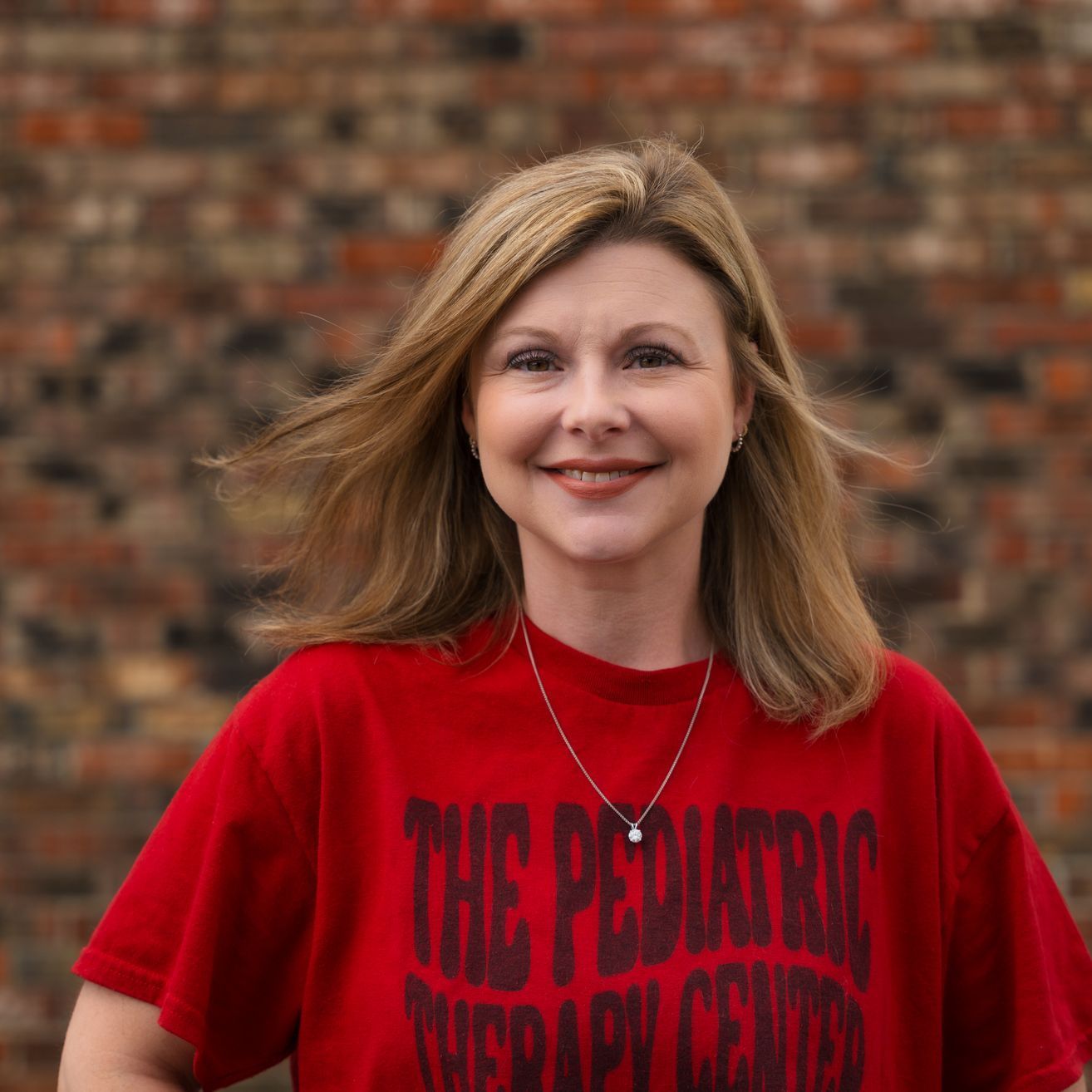 A woman wearing a red shirt that says the pediatric therapy center