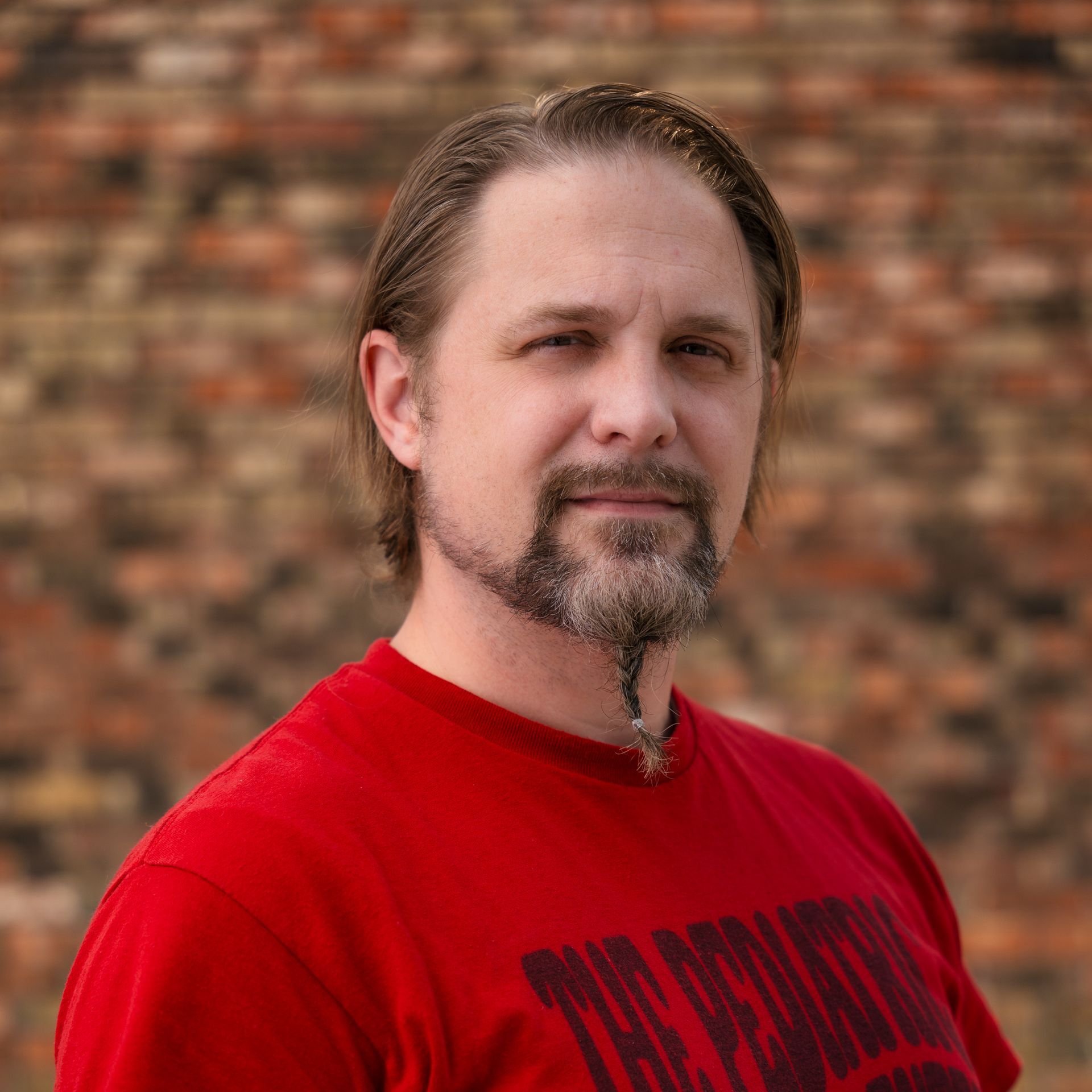 A man with a beard is wearing a red shirt that says the rolling stones