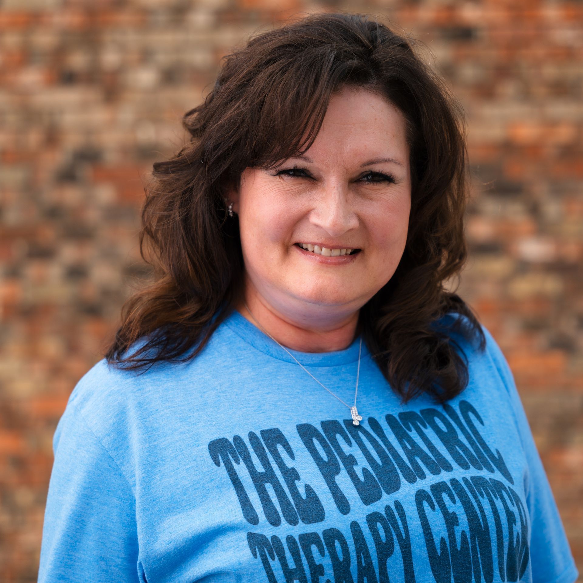 A woman wearing a blue shirt that says the pediatric therapy center