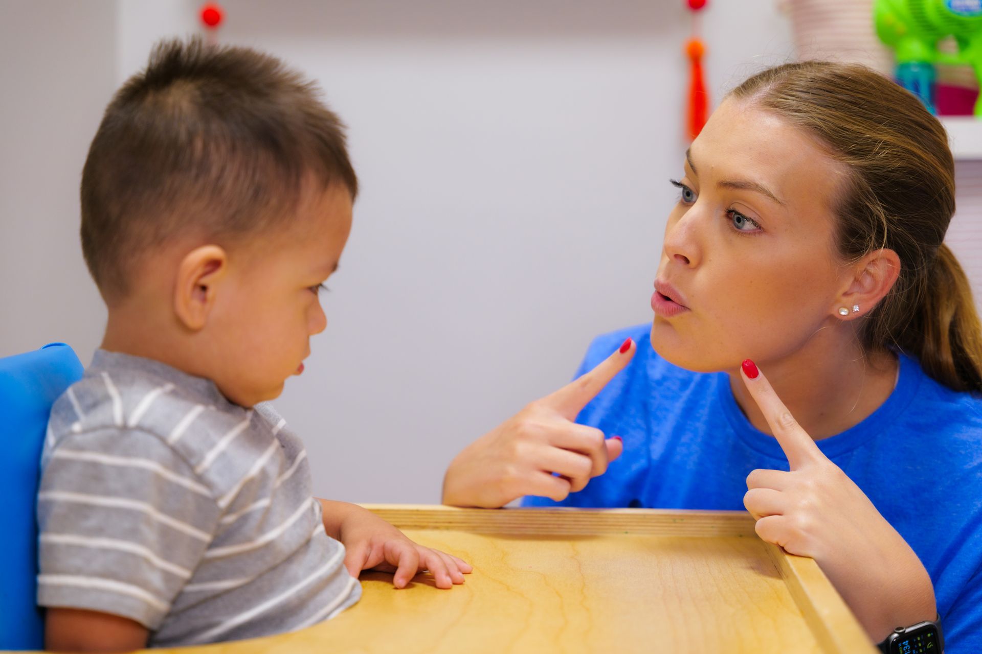 A woman is talking to a baby who is sitting at a table.