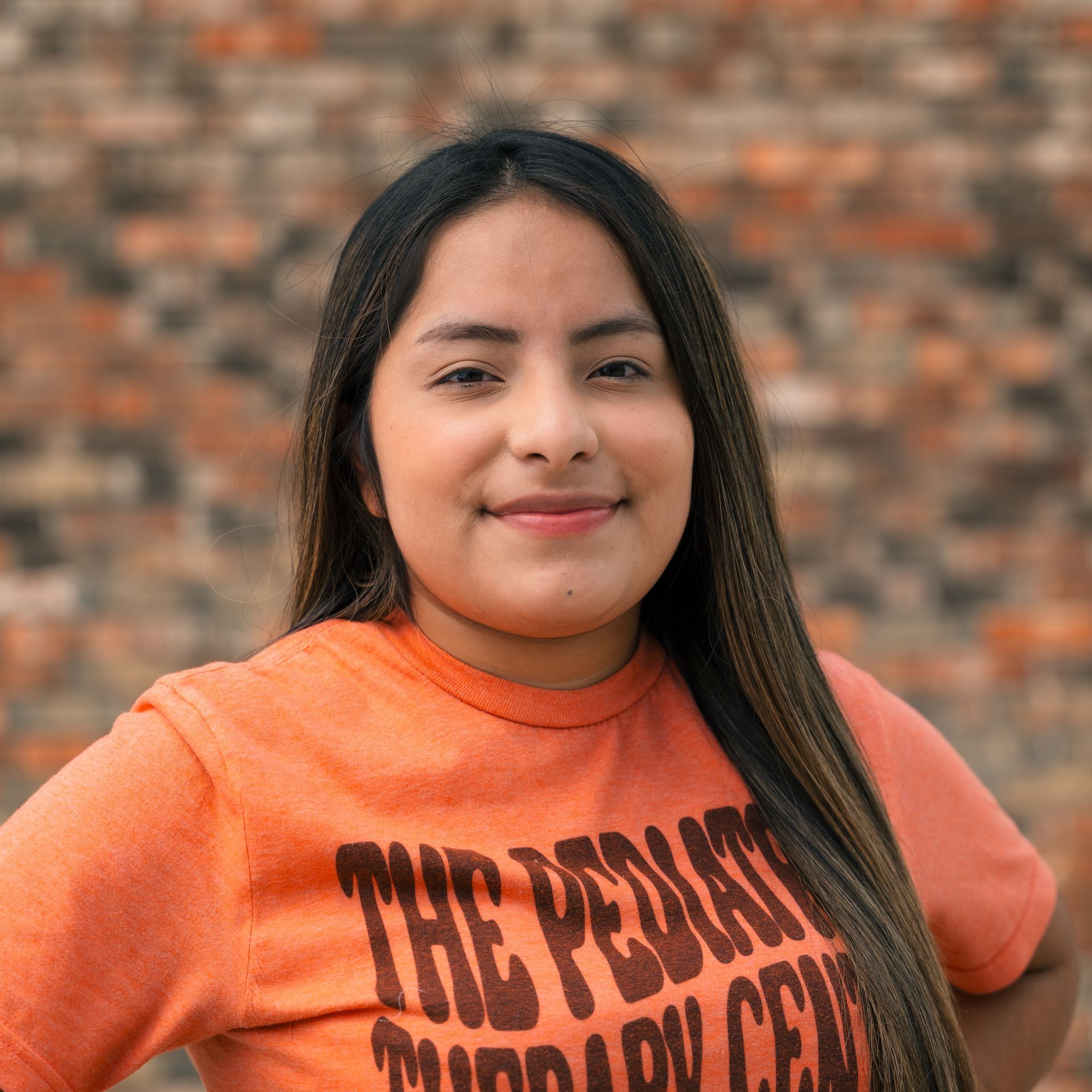 A woman wearing an orange shirt that says the pediatric therapy center