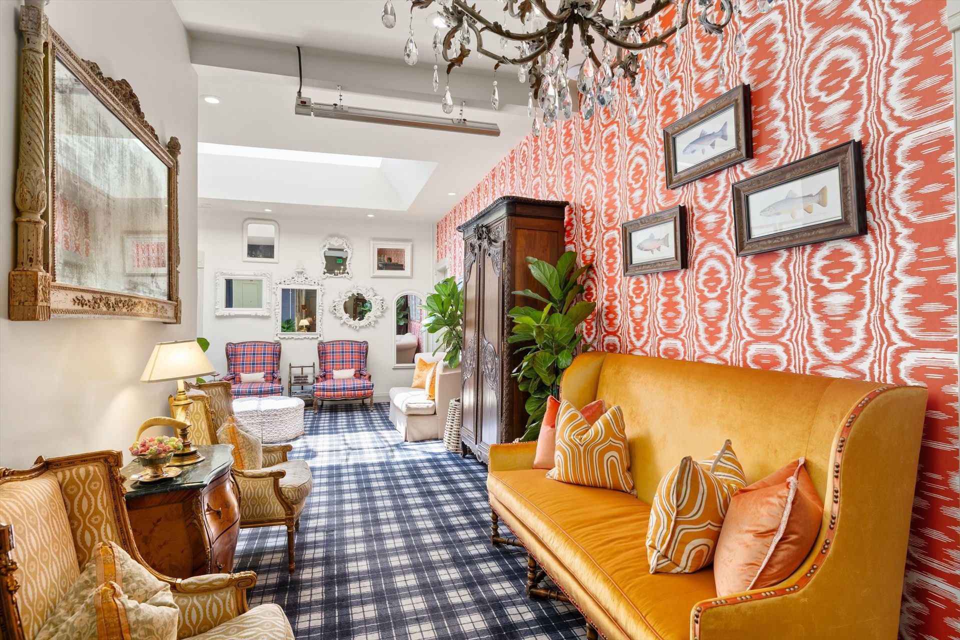 An ornate, antique-filled interior with a plush yellow couch against a red and white patterned wall. Various mirrors and seating line the room.