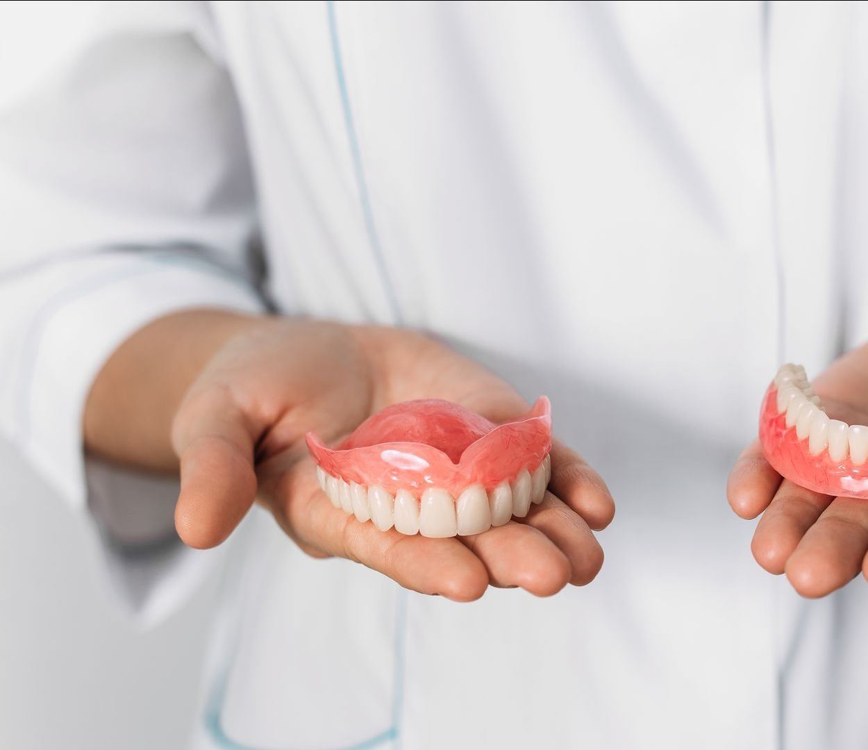 Un dentiste tient deux prothèses dentaires dans ses mains.
