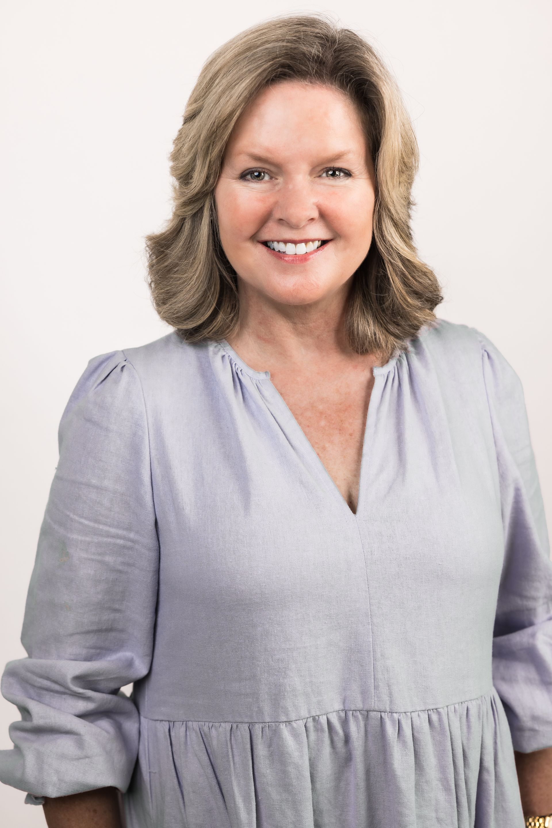 A woman is sitting at a desk with a laptop and a vase of flowers.