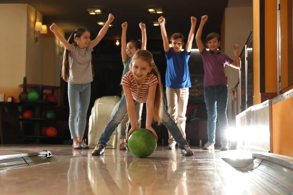 little girl holding a green bowling ball