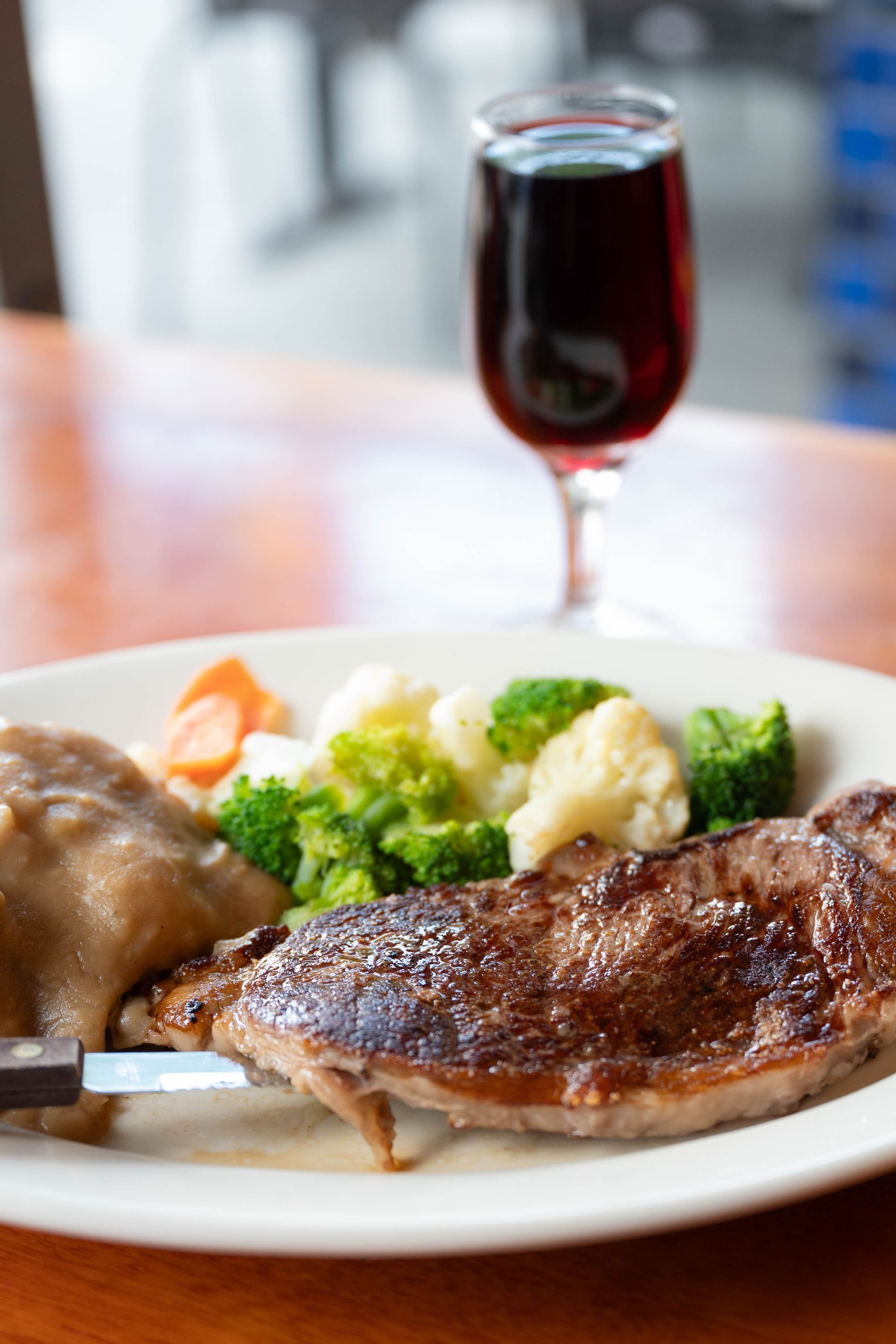 Steak dinner with vegetables and a glass of red wine on a restaurant table
