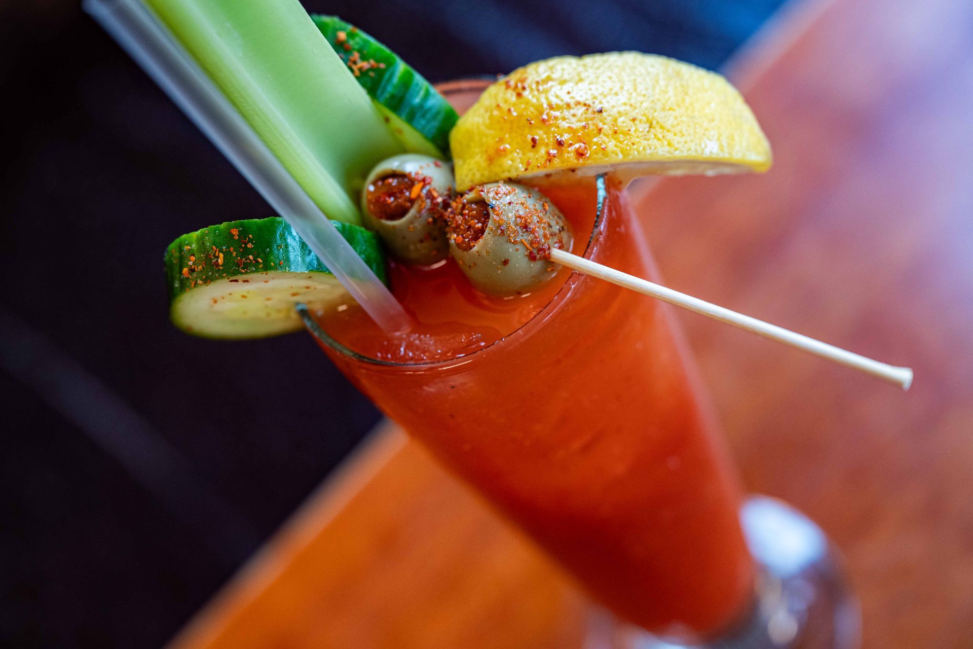 Bloody Mary cocktail garnished with celery, olives, lemon, and a shrimp on a skewer