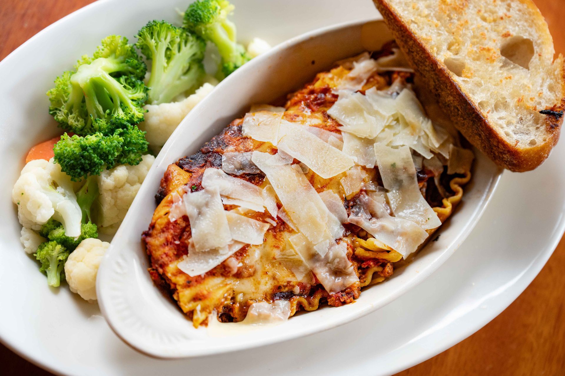 Pasta bake with melted cheese and toast in a white dish, served with broccoli on the side