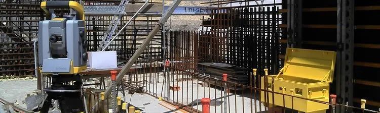 A construction site with a fence and a machine in the foreground.