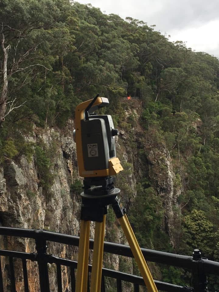 A tripod is sitting on a railing overlooking a cliff.