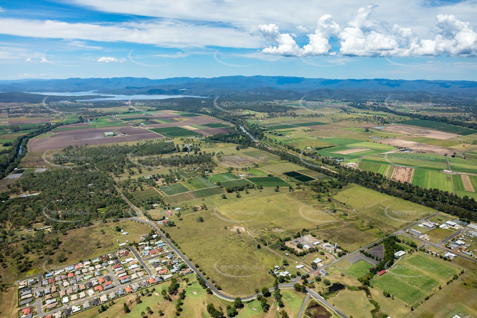 An aerial view of a lush green landscape with mountains in the background.