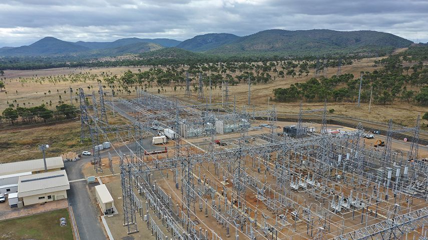 An aerial view of a power station with mountains in the background.