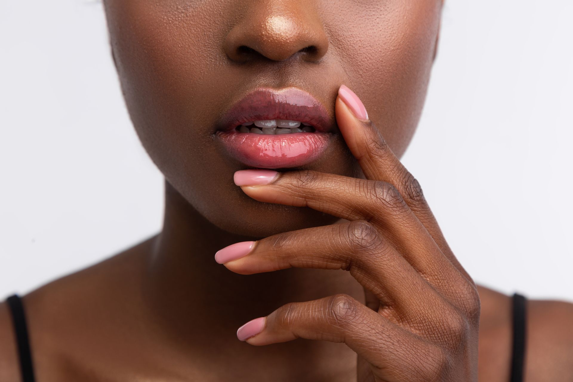 Un gros plan du visage d'une femme aux ongles roses