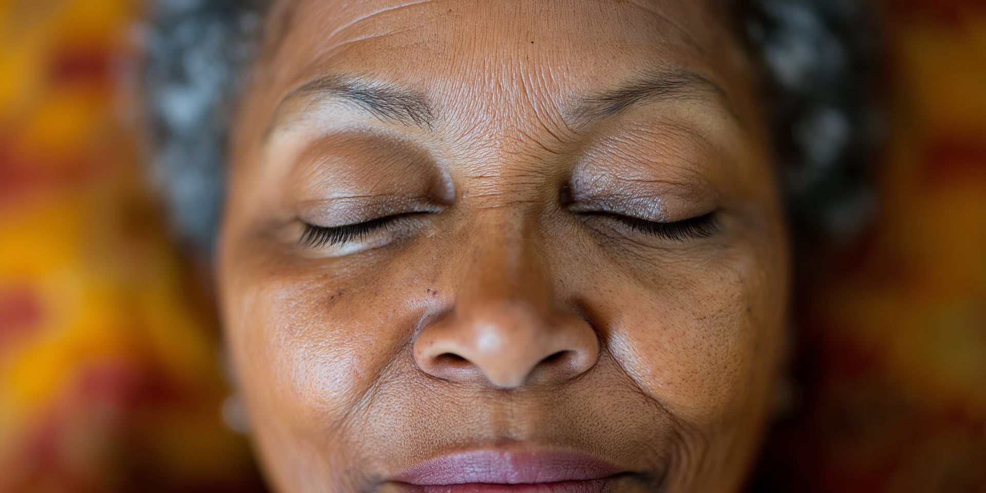 Un gros plan du visage d'une femme âgée avec les yeux fermés.