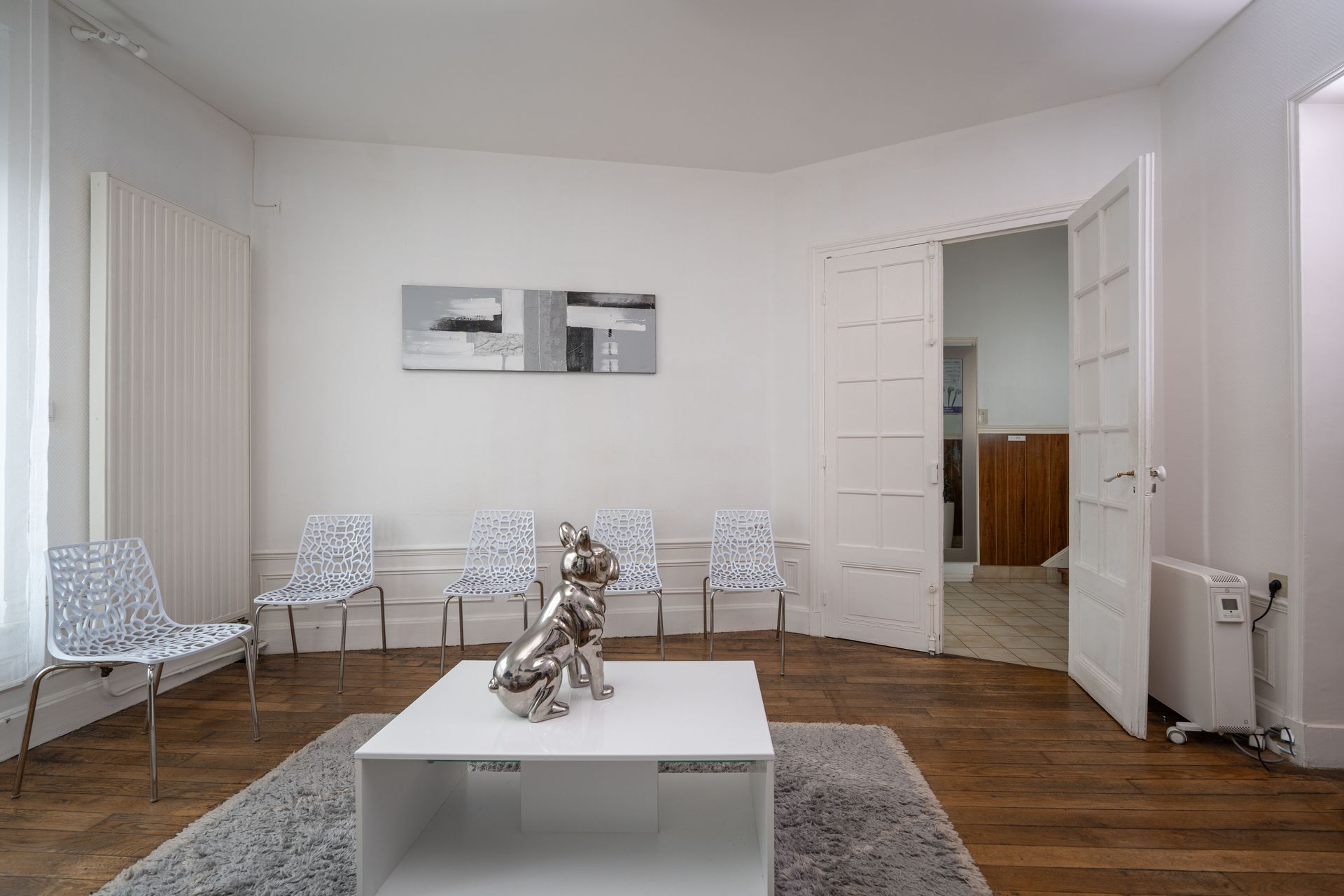 Une salle d'attente avec des chaises blanches et une table basse blanche