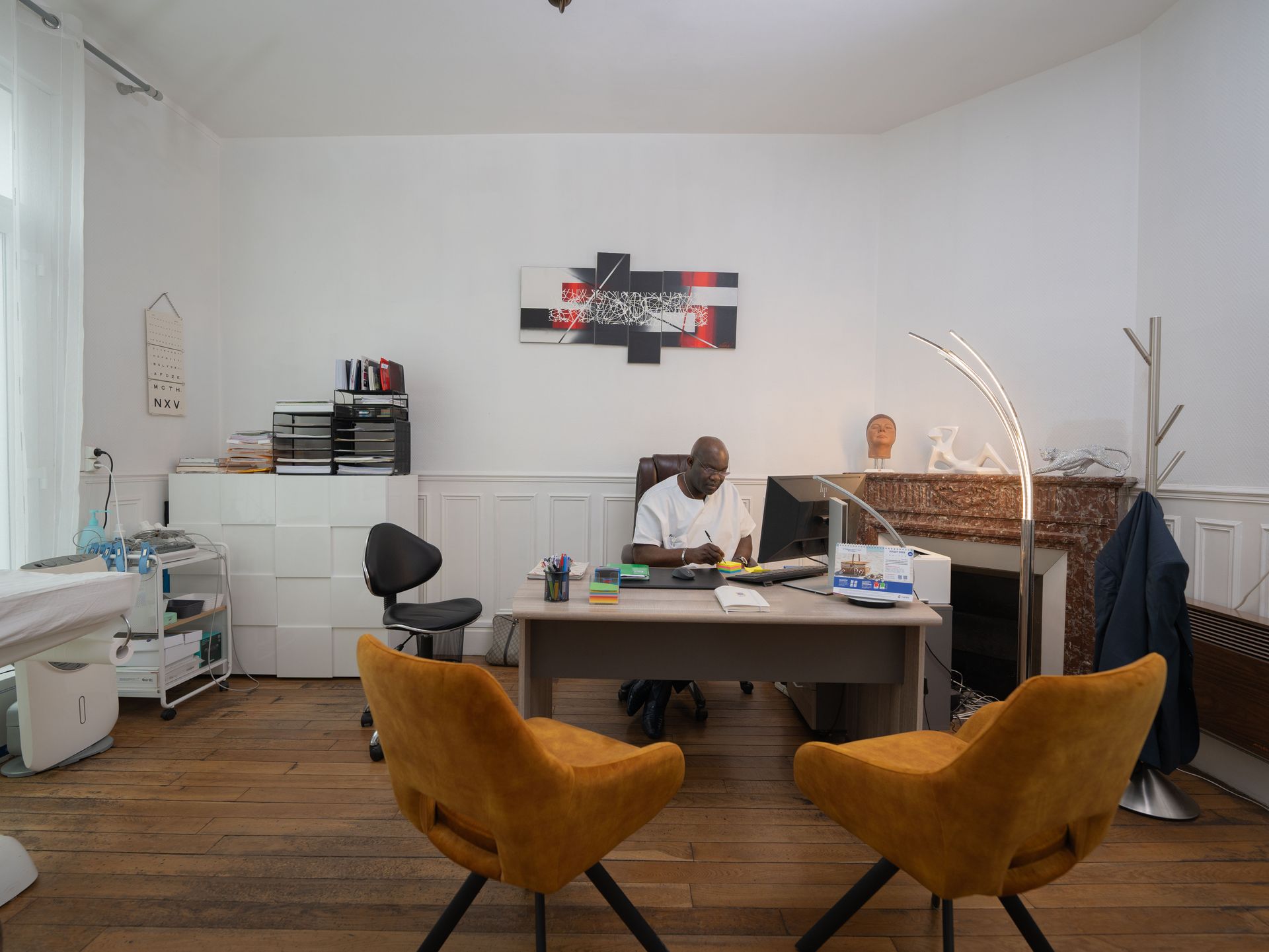 Un homme est assis à un bureau dans une pièce avec deux chaises