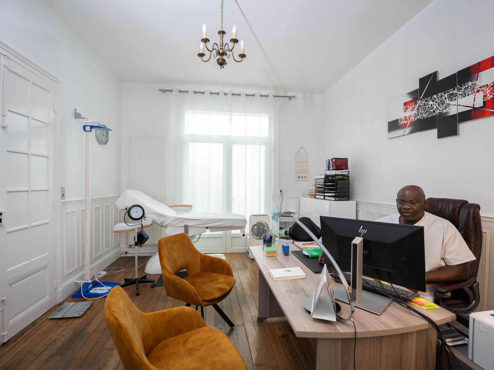 Un homme est assis à un bureau dans une pièce avec deux chaises