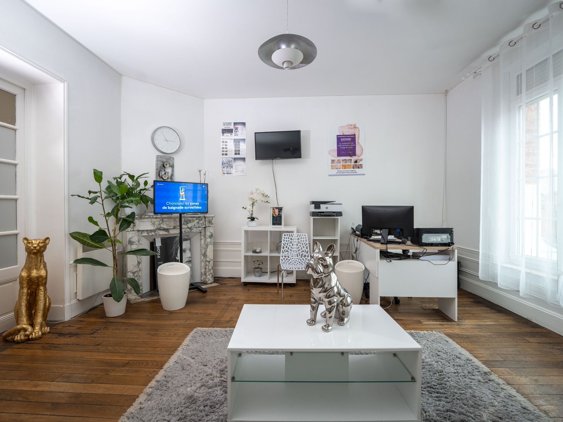 Un salon avec une table basse blanche et une télévision à écran plat