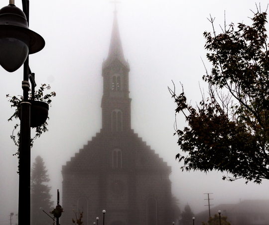 Uma igreja é mostrada em silhueta contra um céu nebuloso