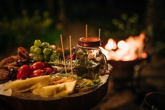 Uma mesa de madeira coberta com comida variada e um pote de azeite.