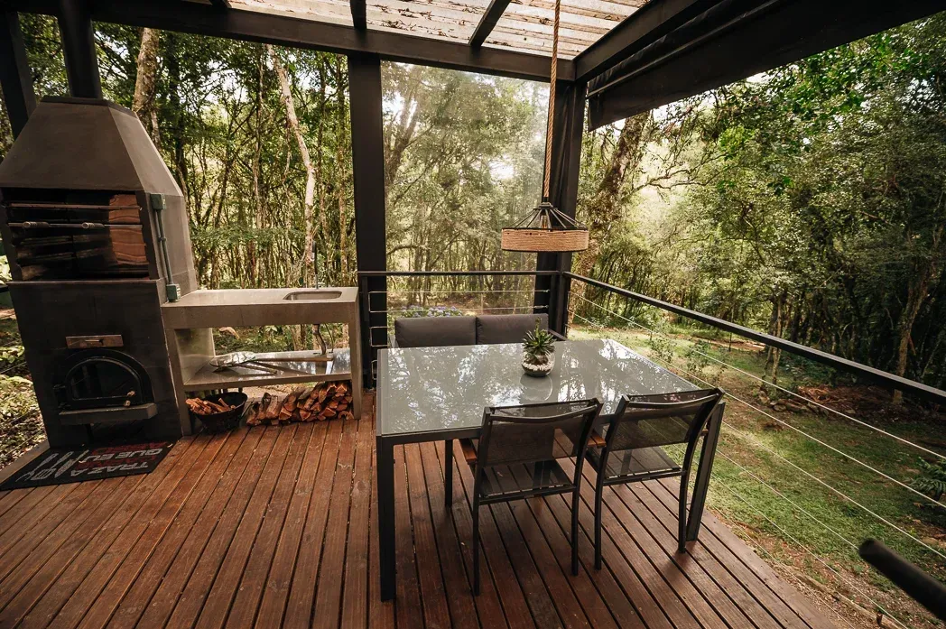 Um deck de madeira com mesa e cadeiras e churrasqueira.