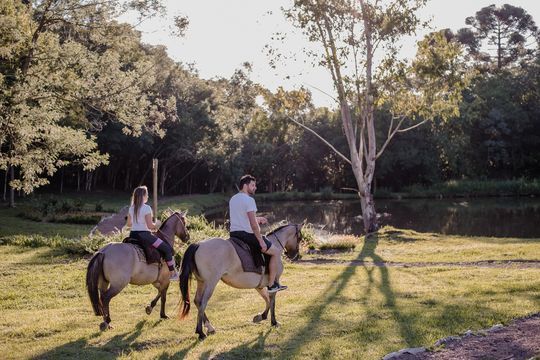 Um homem e uma mulher estão andando a cavalo em um campo.