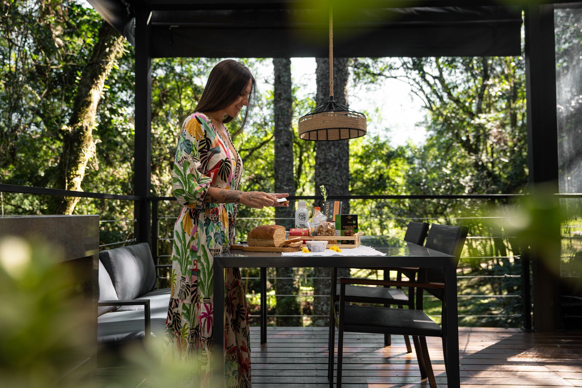 Uma mulher está parada em frente a uma mesa de jantar em um deck.