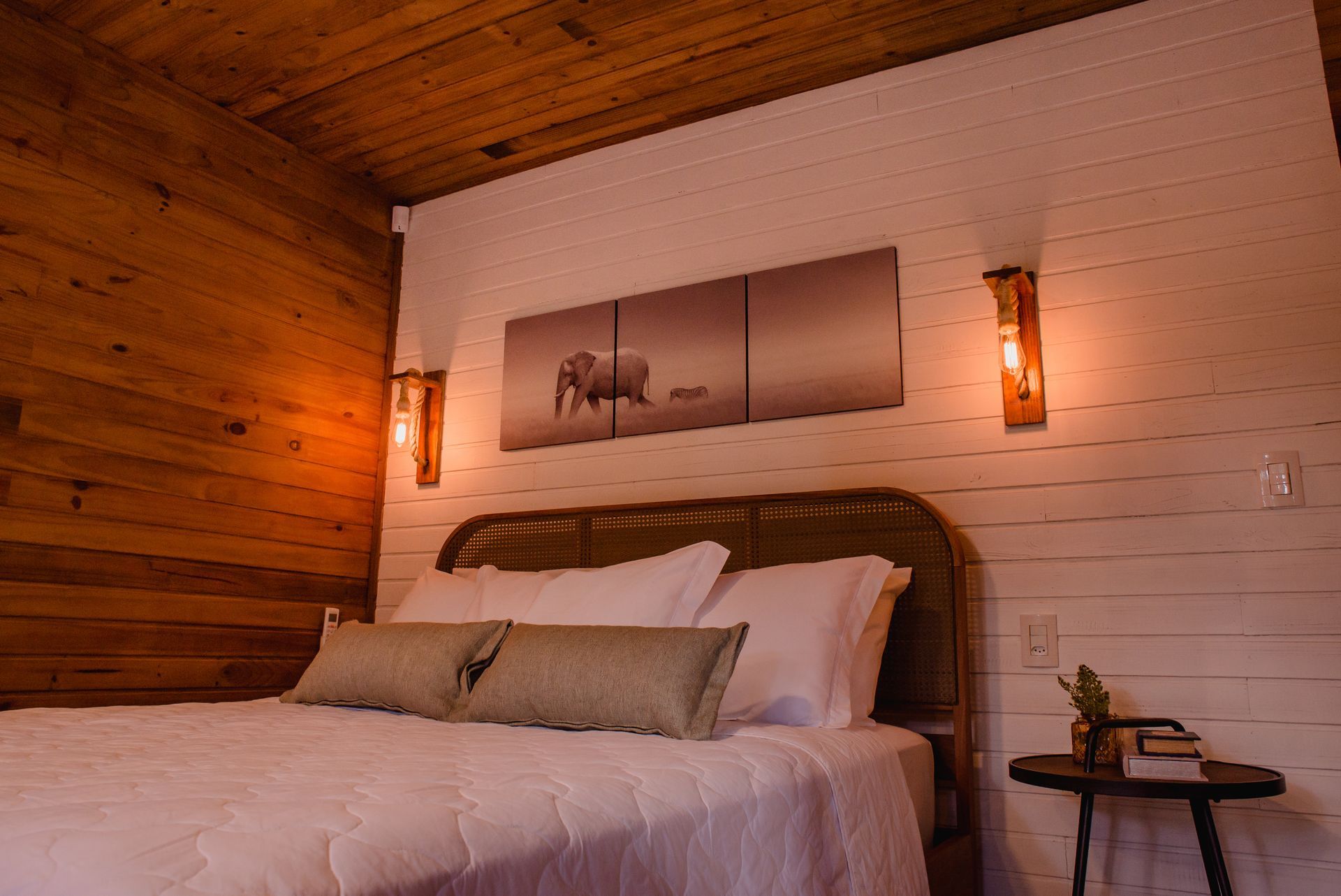 Um quarto com cama, mesa e quadro na parede.
