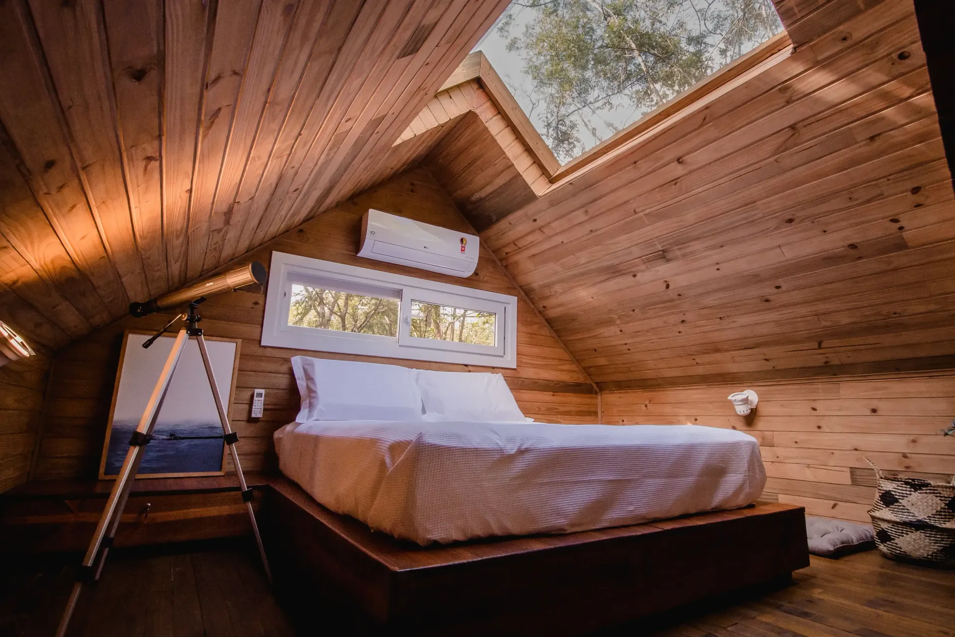 Um quarto com cama e telescópio no sótão.