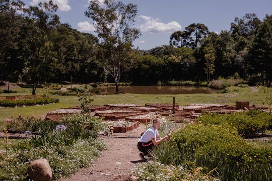 Um menino está ajoelhado em um jardim.