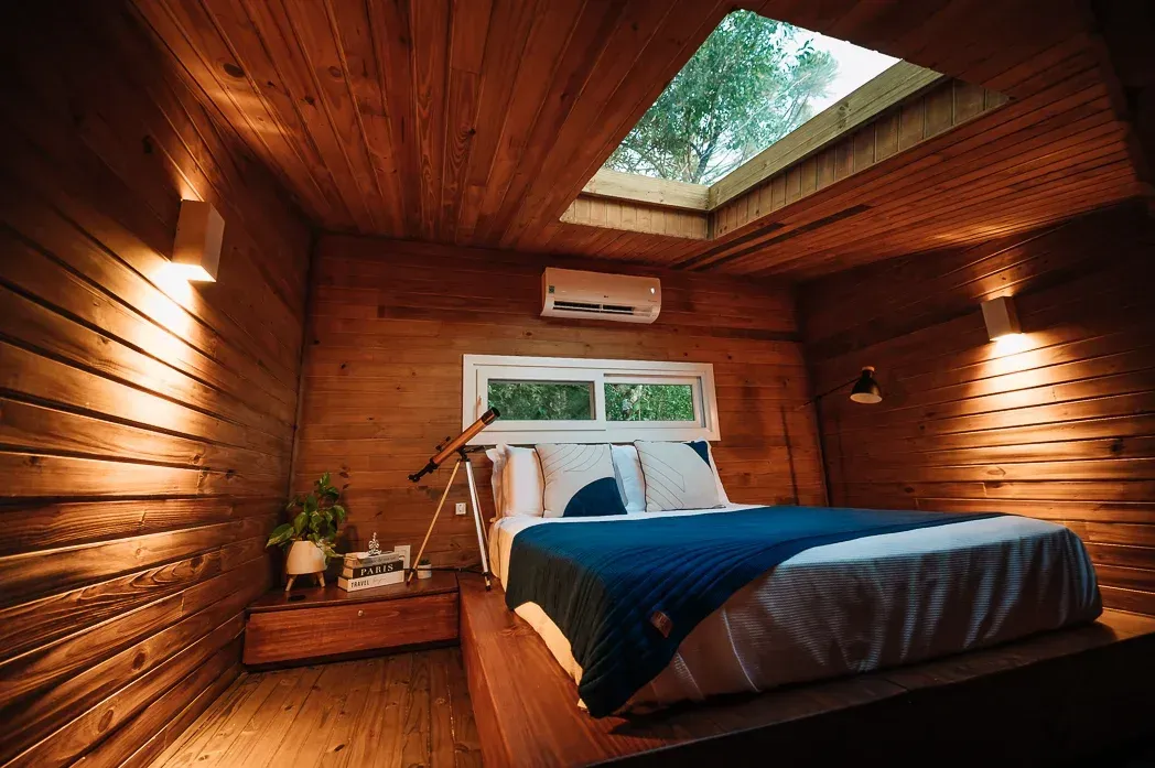 Um quarto com cama e clarabóia no teto.