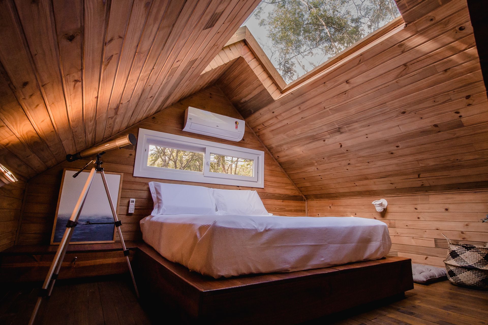 Há uma cama no sótão de uma casa de madeira.