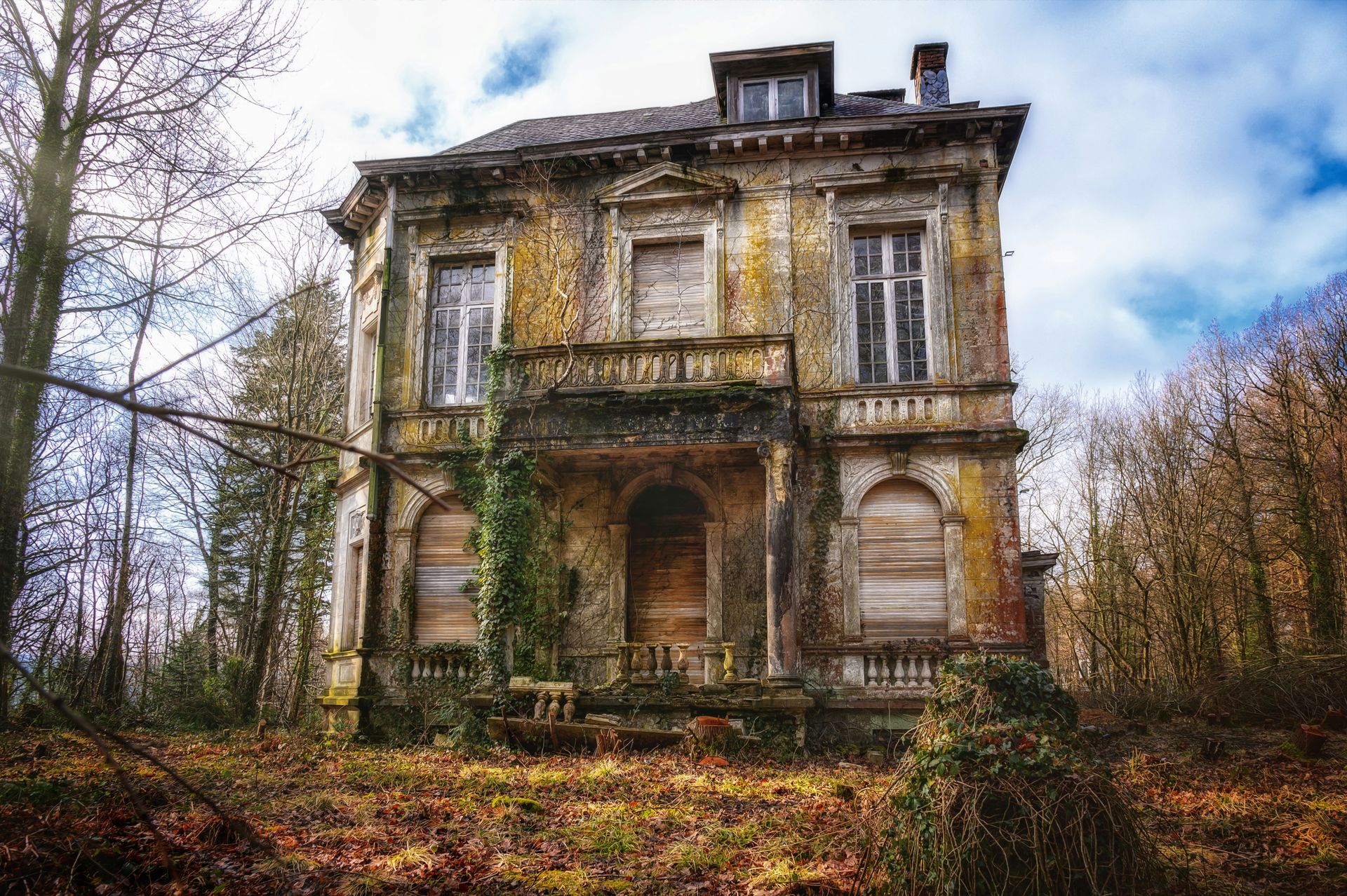 A photo of an old house with mold, dried up lawn, and worn out exterior.
