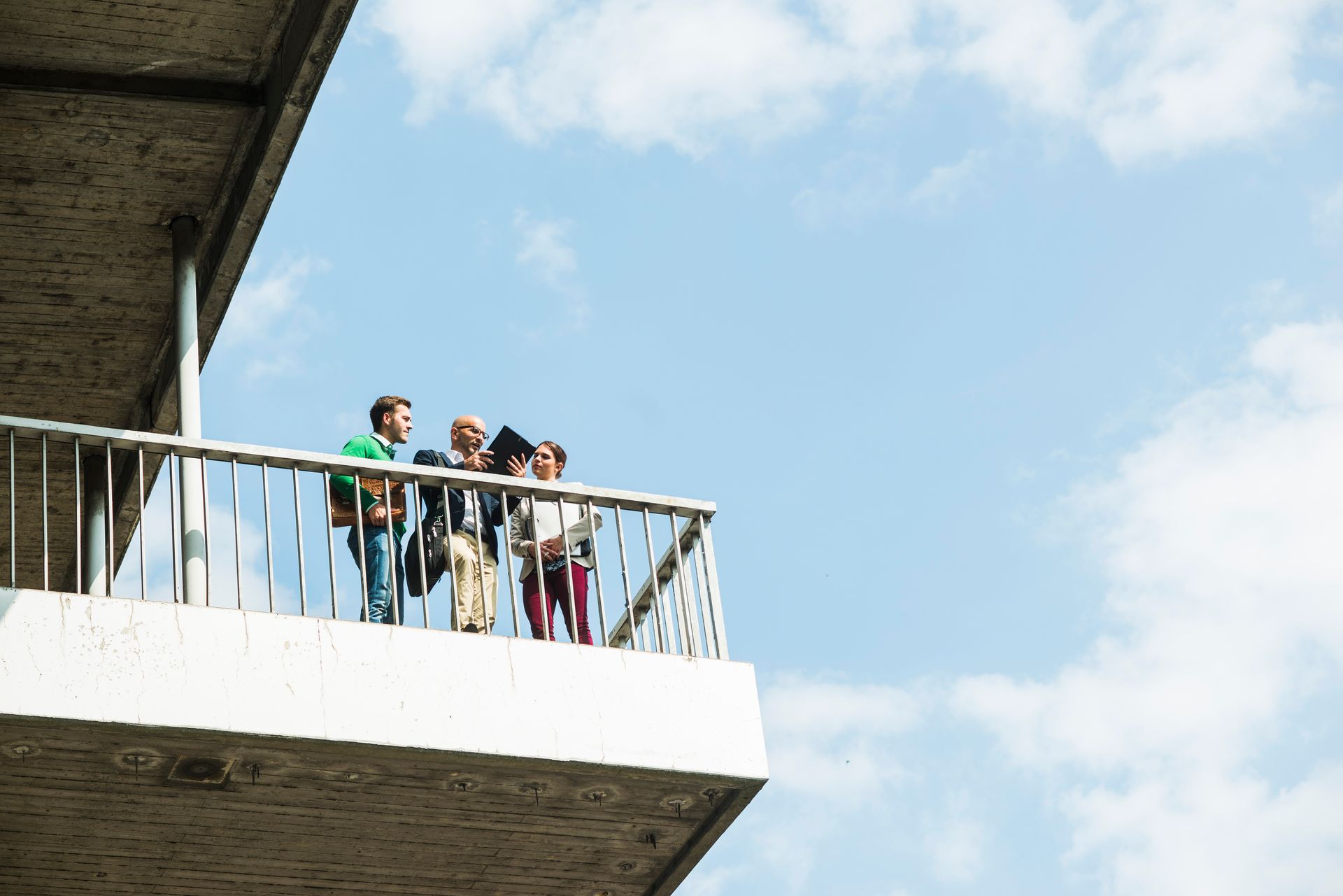 A group of people are standing on a balcony looking at the sky.