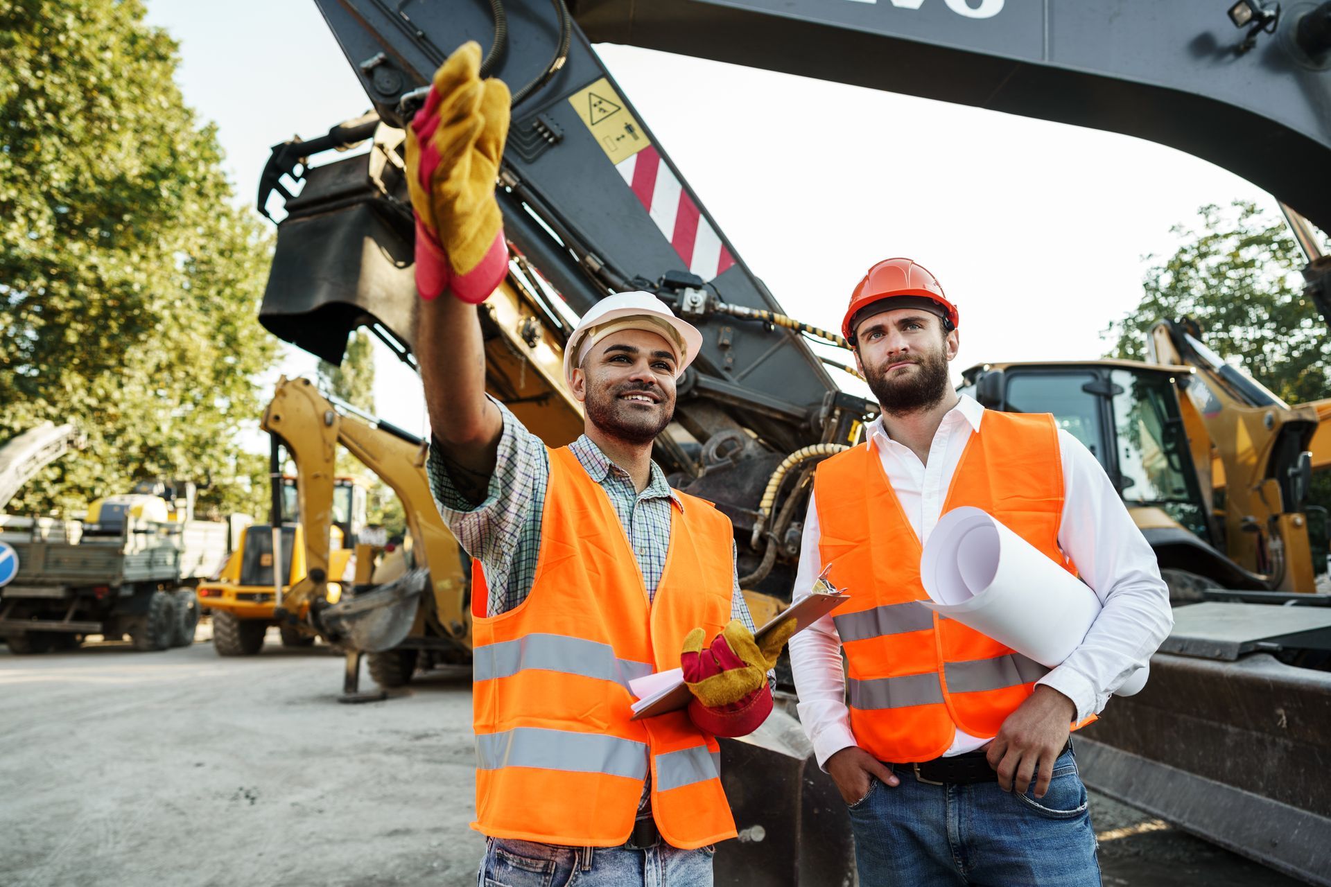 Two construction workers are standing next to each other in front of a construction site.