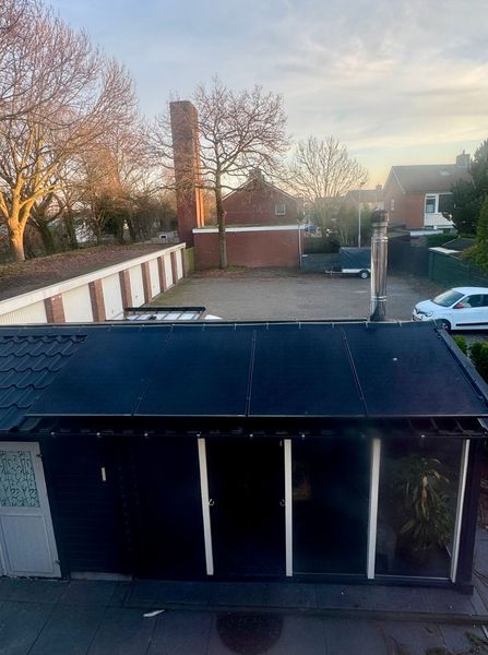 Een laadpaal voor elektrische voertuigen op een bakstenen muur met een bordje. Het nummer 24 is erboven zichtbaar.