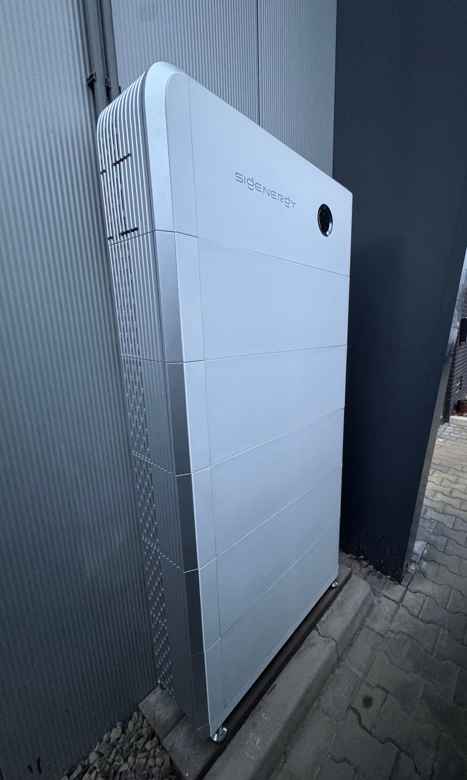 Thuisbatterij van Sigenergy, buiten gemonteerd, vlakbij de muur van een gebouw.
