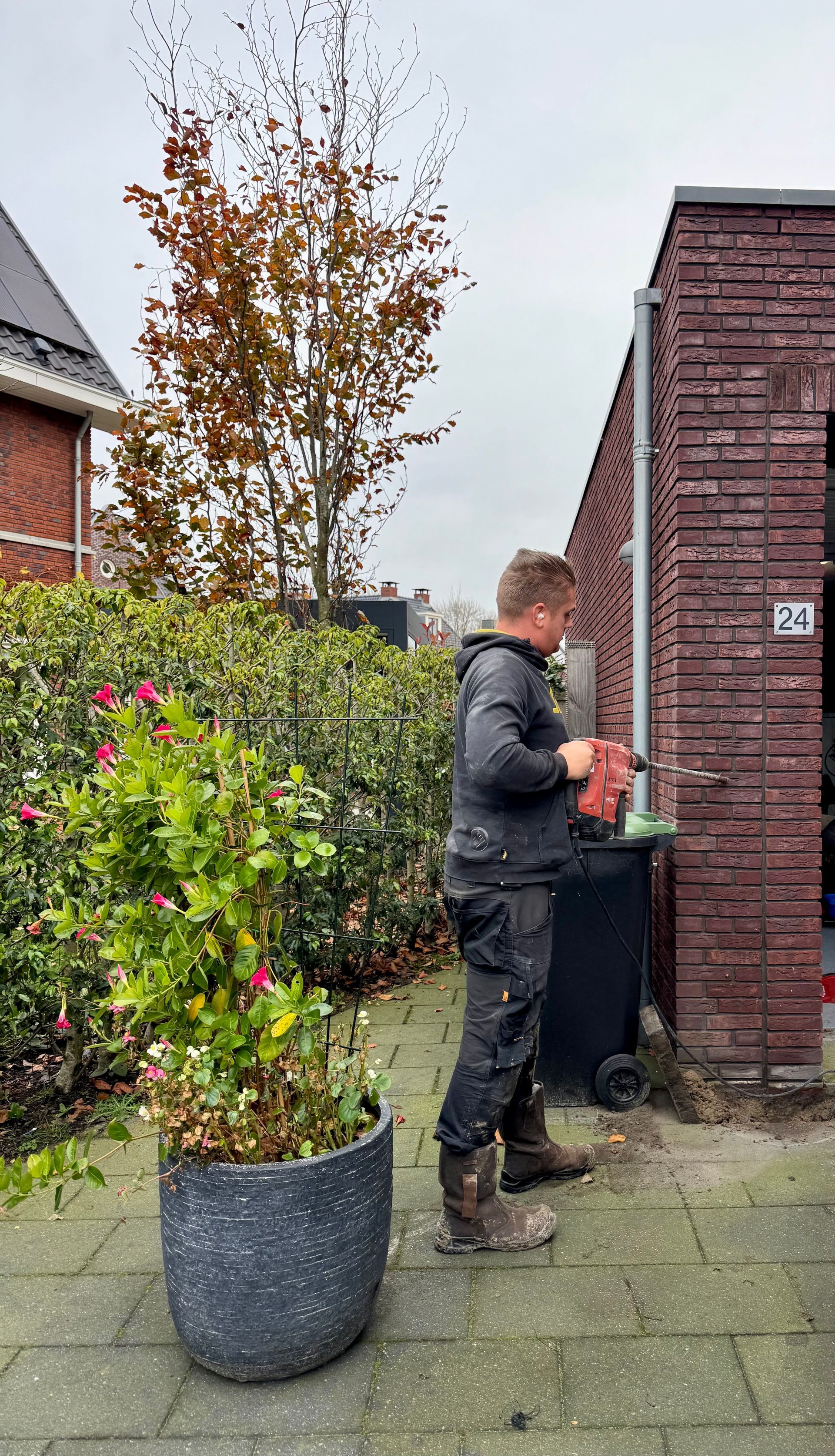 electricien boort gat in muur om autolader te kunnen monteren.