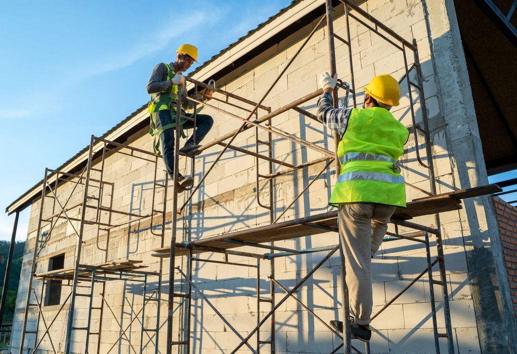 Due operai edili stanno lavorando su un edificio su un'impalcatura.
