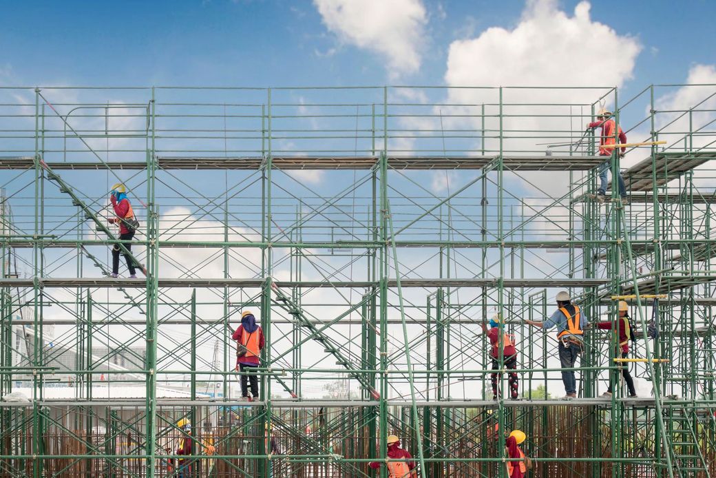 Un gruppo di operai edili sta lavorando su un'impalcatura in un cantiere.