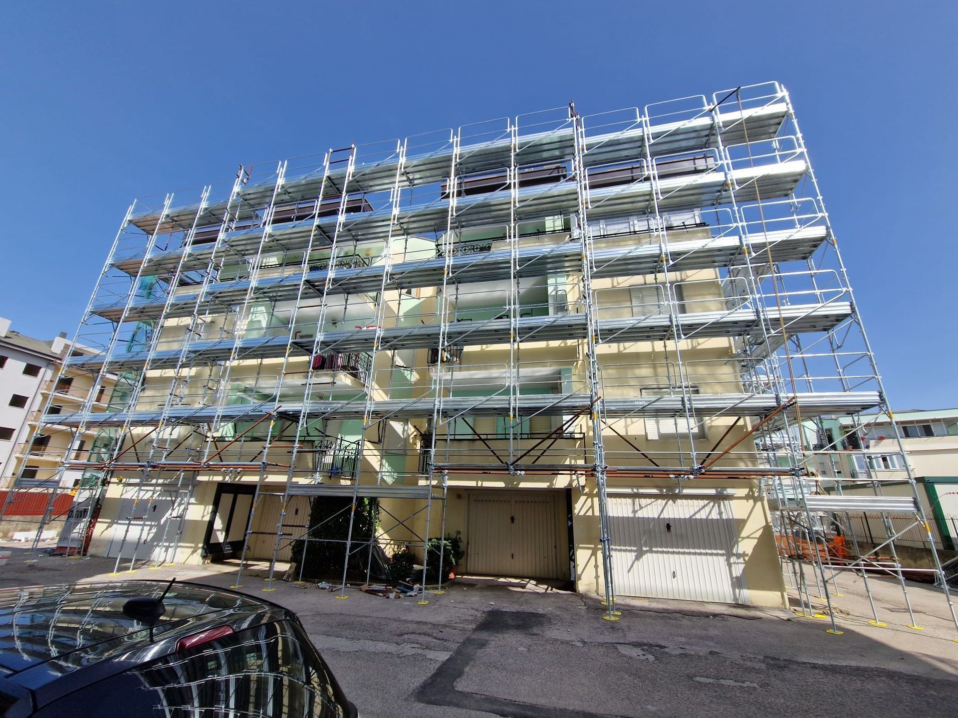 Un edificio in costruzione circondato da impalcature e con un'auto parcheggiata davanti.